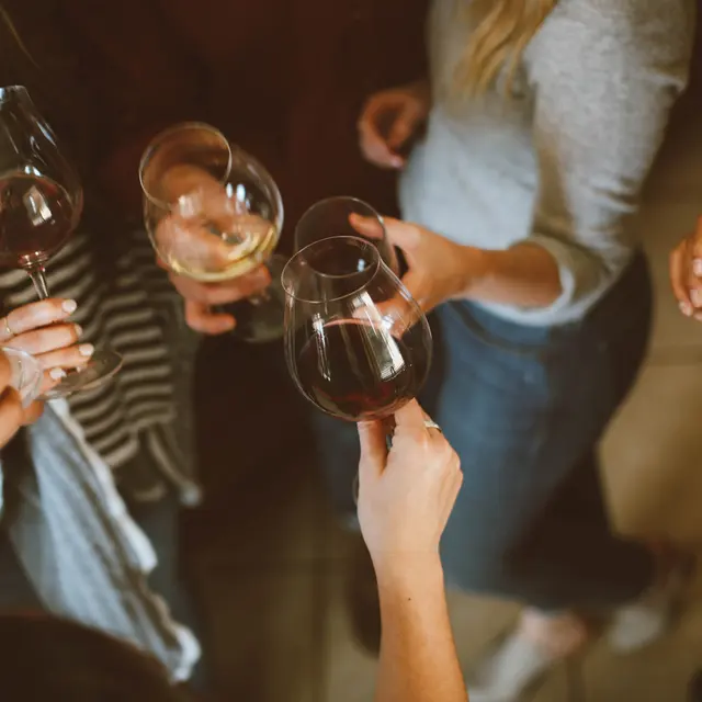High Street Lofts Group of people raising wine glasses in a toast, with a mix of red and white wine, in a cozy setting.