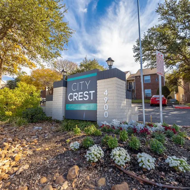 Sign for City Crest apartments with a street number and decorative landscaping in front.