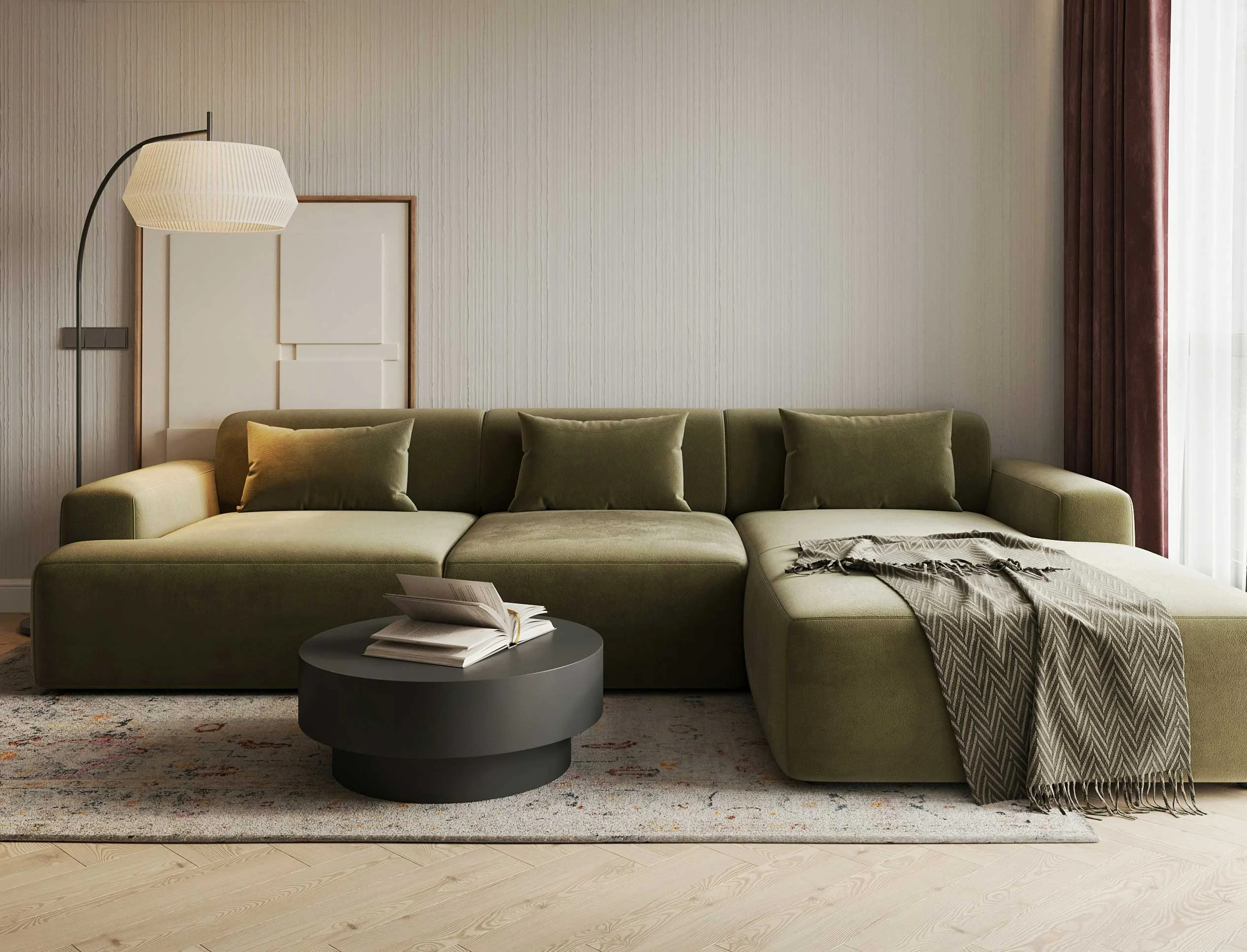 Stylish Modern Living Room A modern living room featuring a spacious green sectional sofa with multiple cushions, a black coffee table in front, and a warm blanket draped over the sofa. There is a unique lamp overhead and a light-colored rug on the floor.