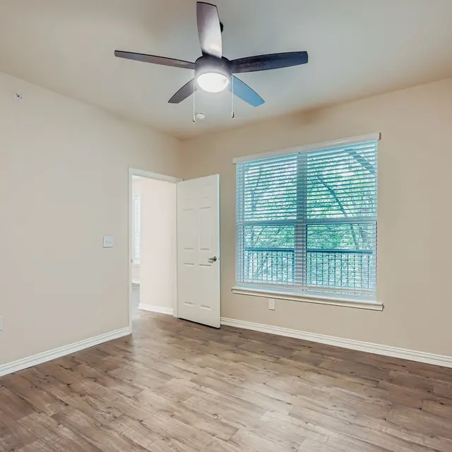 Empty Modern Bedroom A spacious, empty bedroom with a ceiling fan and a window.