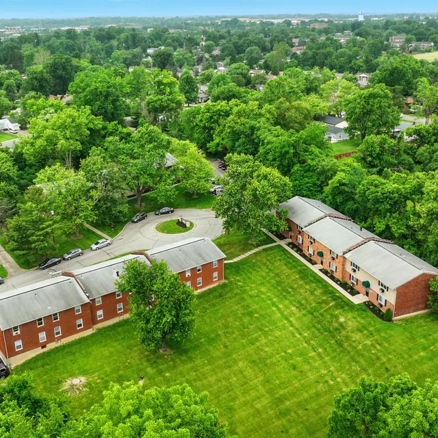 Aerial view of a residential area featuring green trees and parking spaces next to low-rise buildings.