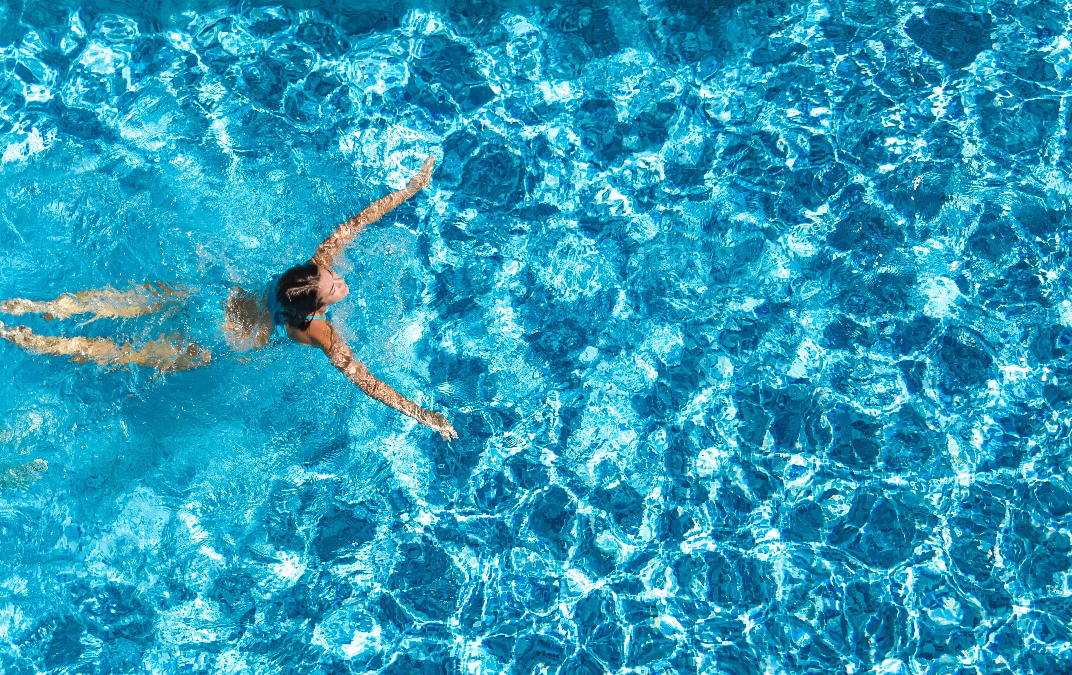 A swimmer glides through clear blue water in a swimming pool.