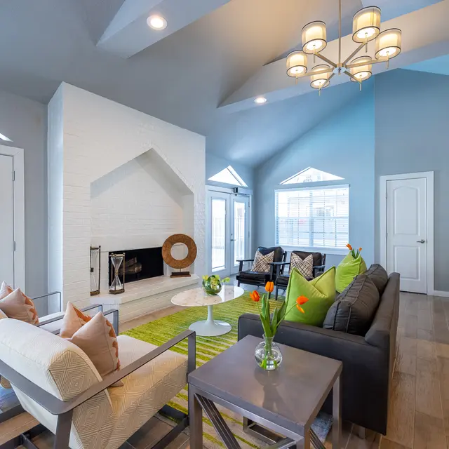 Stylish Modern Living Room A modern living room with a light color palette featuring a white stone fireplace, comfortable seating, and large windows that allow natural light.