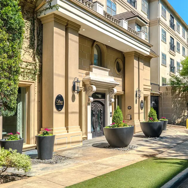 The entrance of a modern building featuring elegant architecture and landscaping.