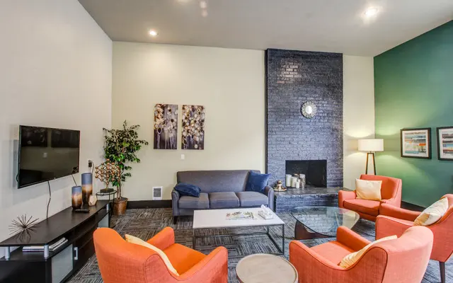Modern Living Room Interior Modern living room with orange chairs and gray couch, featuring a fireplace and decorative art.