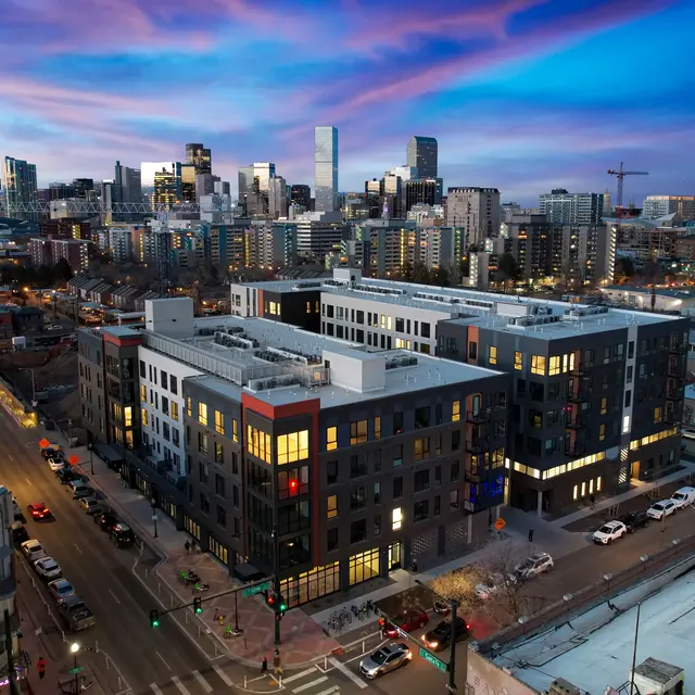 A cityscape at sunset featuring modern buildings and colorful clouds in the sky.