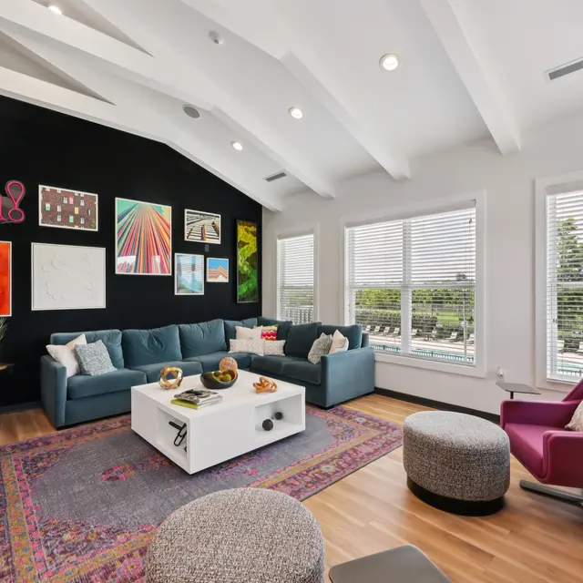 Contemporary Living Room Design A modern living room featuring a dark accent wall with artwork, a blue sectional sofa, a white coffee table, and large windows allowing natural light in.