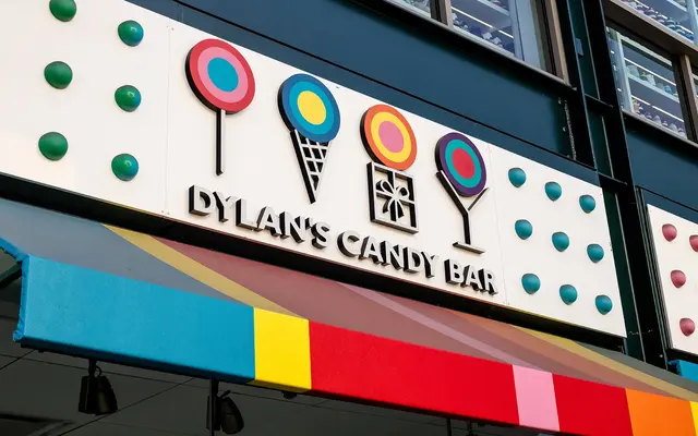 Colorful storefront sign of Dylan's Candy Bar with candy-themed decorations including lollipops and ice cream cones.