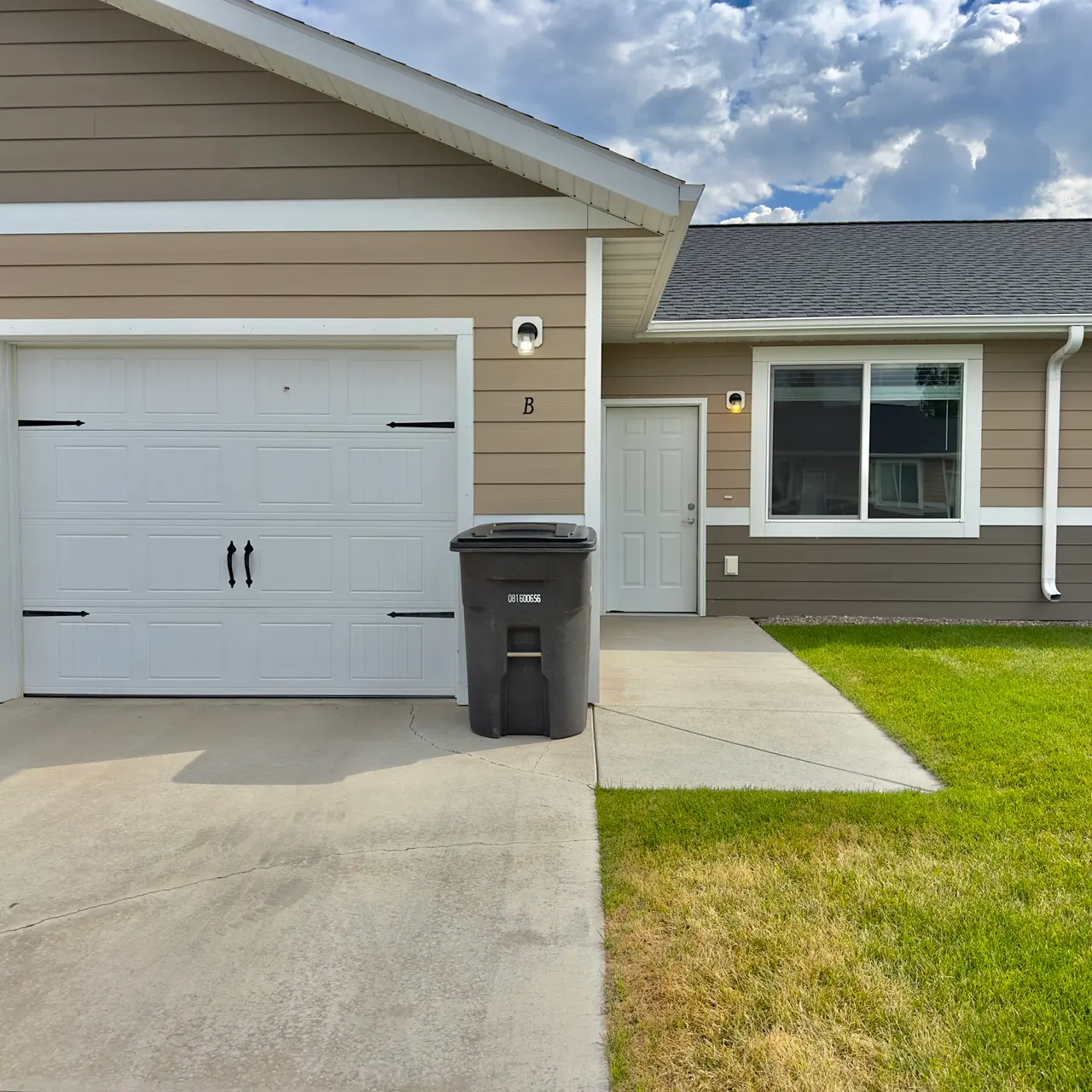 apartment garage Spacious garage with room for vehicles and storage, featuring a sturdy door, ample lighting.