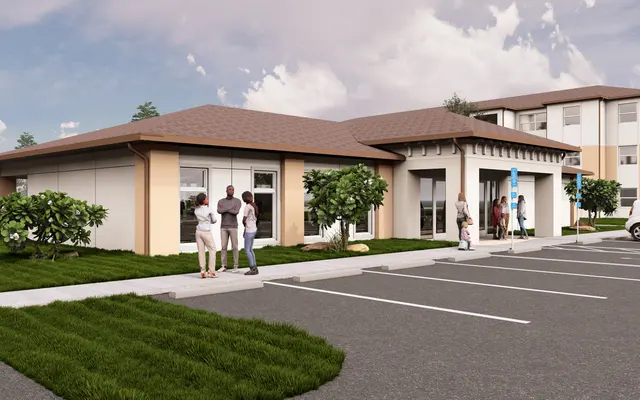 Modern Building Exterior View Exterior view of a modern building with a brown roof, landscaped front yard, and parked cars. People are gathered outside, socializing.