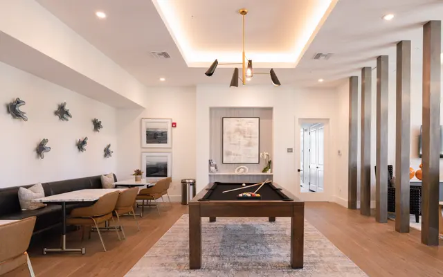 A modern lounge area featuring a pool table, seating, and artwork on the walls.