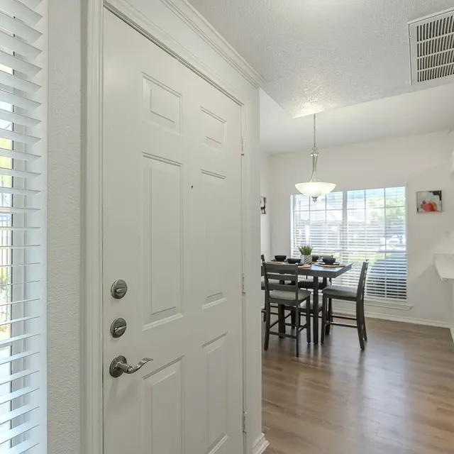 View of an entryway leading to a dining area with a table and chairs.