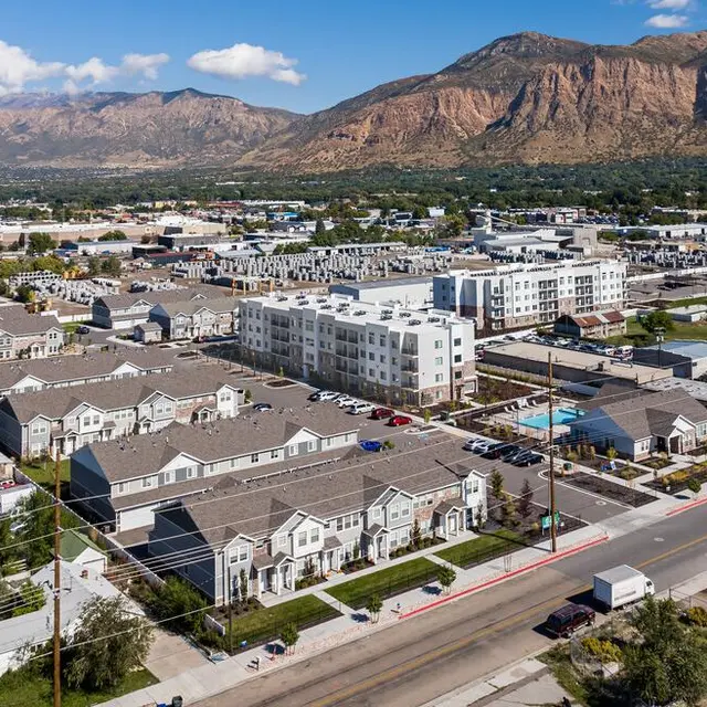 Aerial view of a residential area featuring multiple buildings, with some being low-rise and others mid-rise, surrounded by mountains in the background.