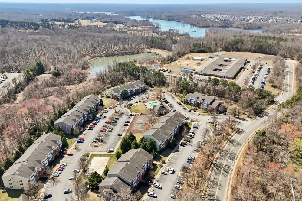 Aerial view of a residential apartment community surrounded by trees and a river.