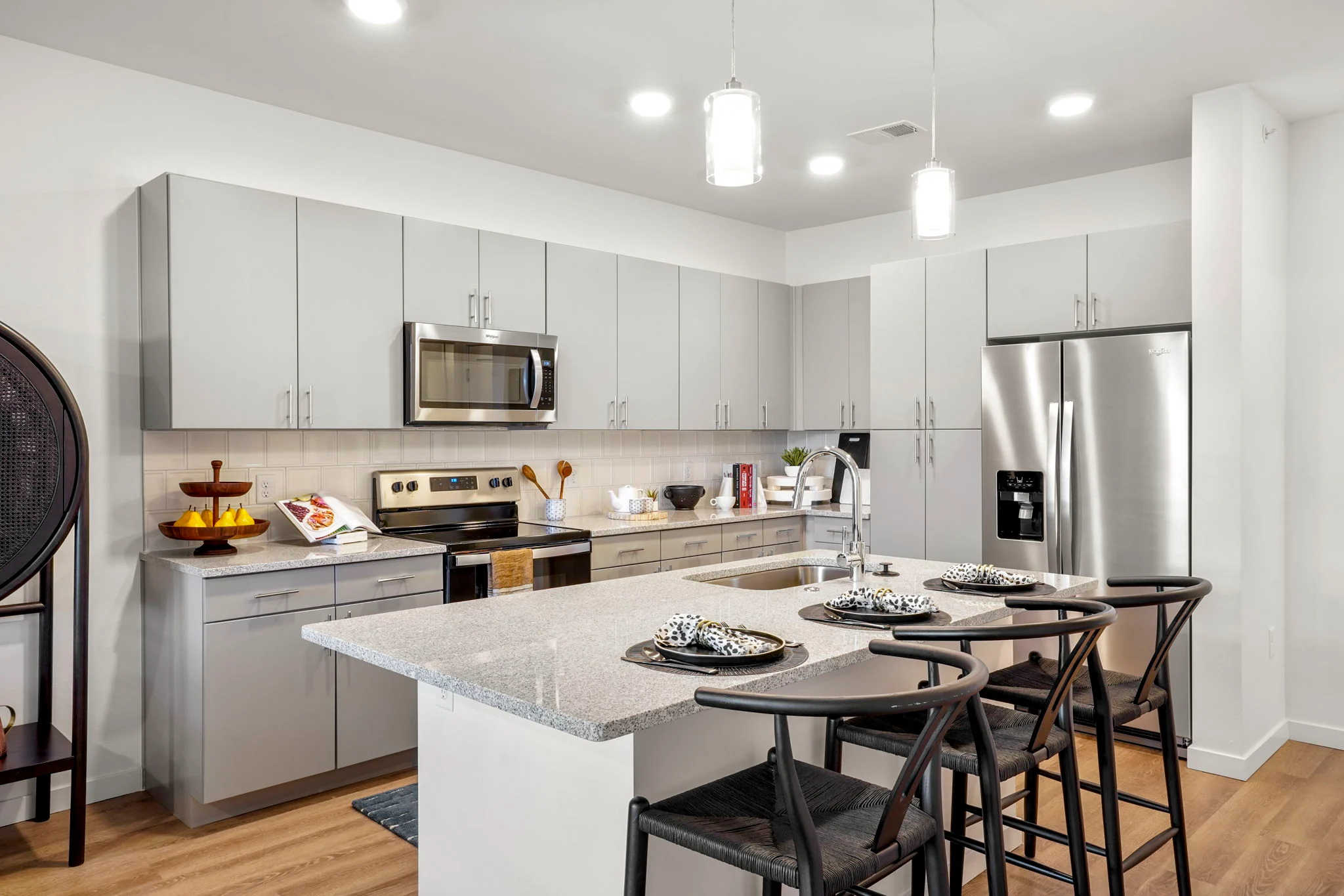 A modern kitchen featuring gray cabinets, stainless steel appliances, and a large island with seating.