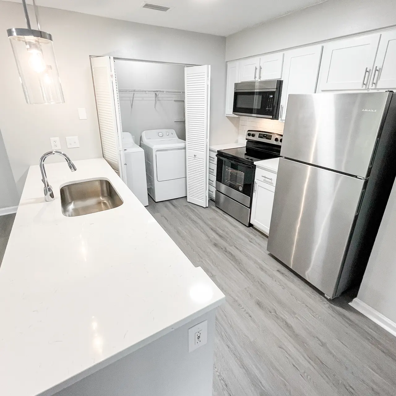 Modern Kitchen with Stainless Steel Appliances A modern kitchen featuring stainless steel appliances, white cabinetry, and a laundry area behind louvered doors.