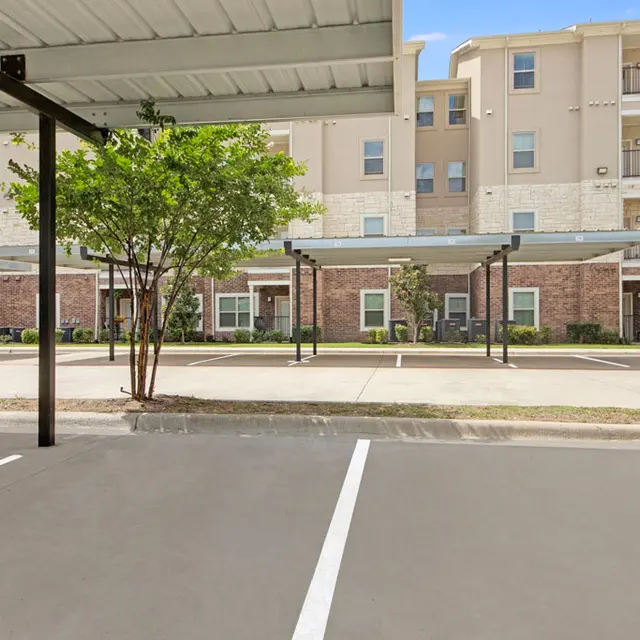 Parking Area of an Apartment Complex A parking area with shaded spaces and apartment buildings in the background.