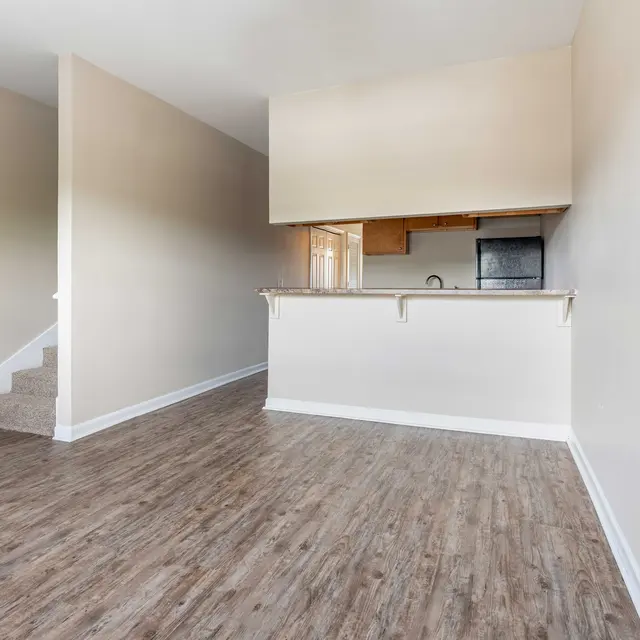 Spacious empty apartment interior with wooden flooring and kitchen area