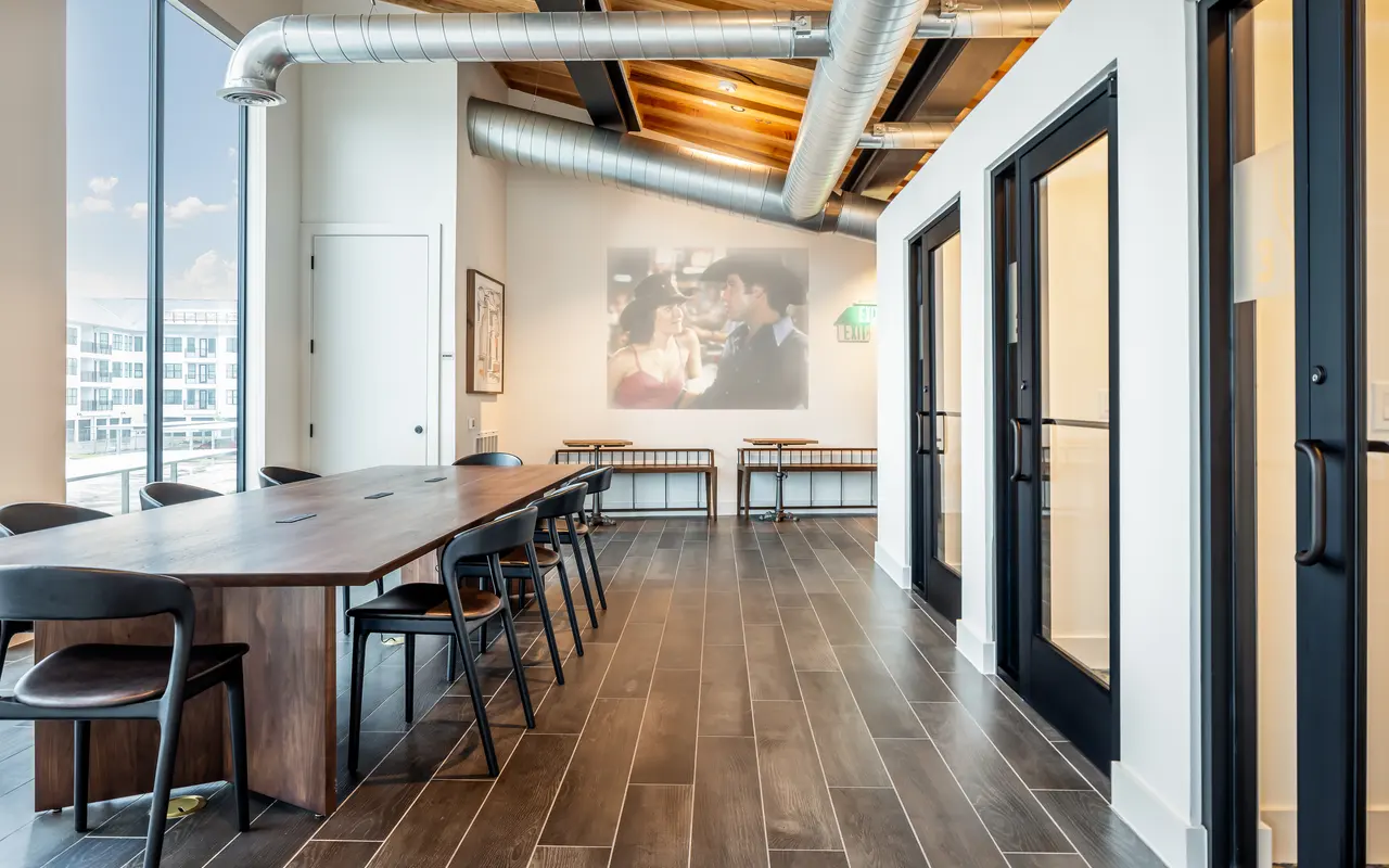 A rectangular table surrounded by eight chairs on hardwood-style flooring, next to a window.