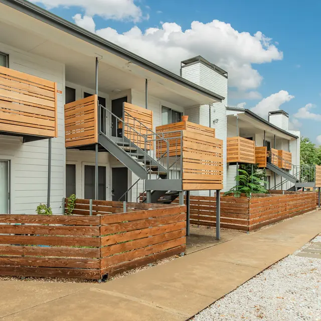 Artisan at South Lamar Walkway beside apartment buildings with fenced-in patios and balconies at Artisan at South Lamar