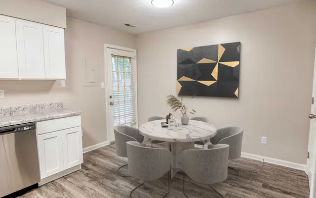 Summit at 501 Modern kitchen with a round dining table, four gray chairs, and a black and gold abstract wall art piece. Natural light from windows.