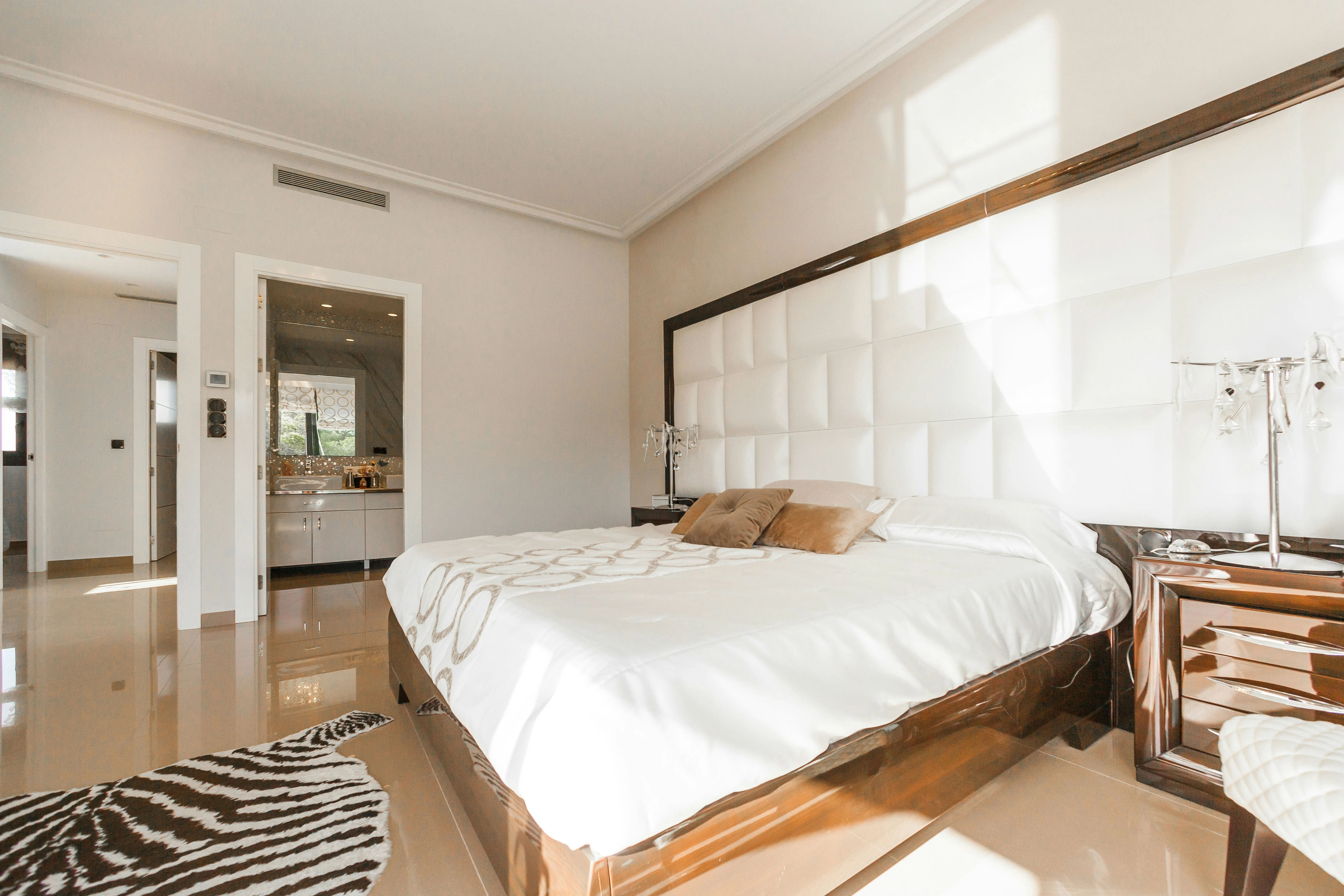 Elegant Modern Bedroom A modern bedroom featuring a large bed with a tufted headboard, elegant wooden nightstands, and a stylish rug.