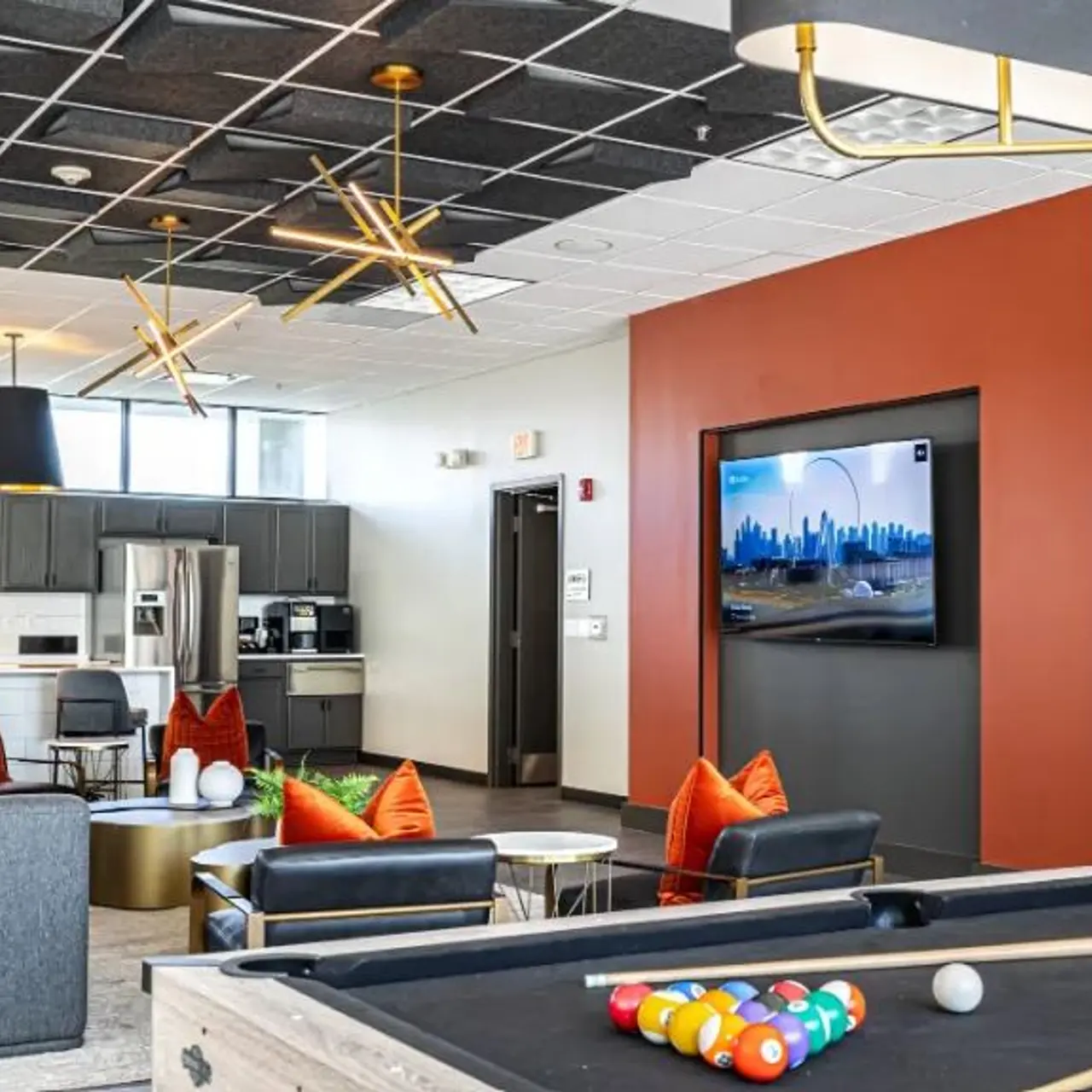 Modern Lounge Area A stylish lounge area featuring a pool table, seating with colorful pillows, and a large TV mounted on the wall.