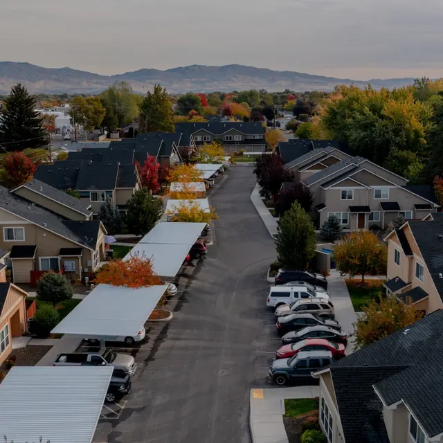 Bowery Point Aerial view of a suburban neighborhood with houses lined along a street, featuring autumn foliage in the trees and a distant mountainous backdrop.
