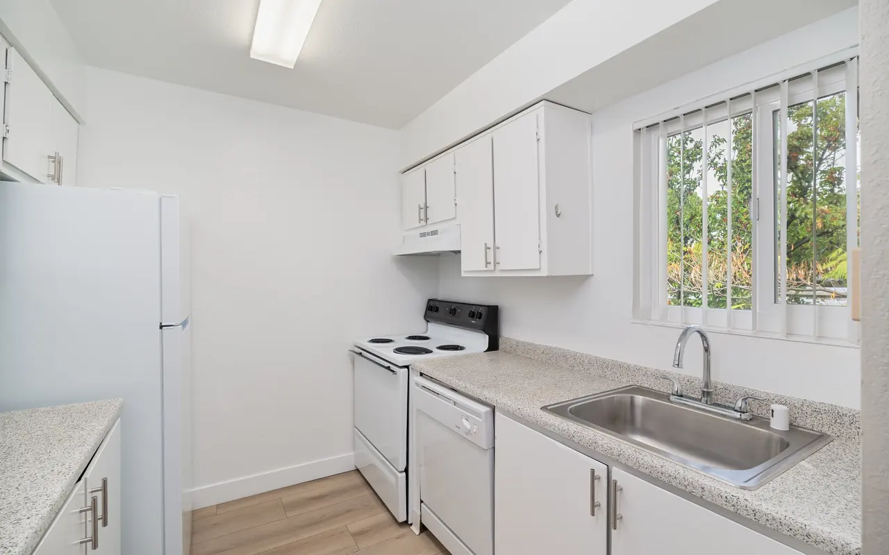 A modern kitchen with white cabinets, a stainless steel sink, stove, and refrigerator.