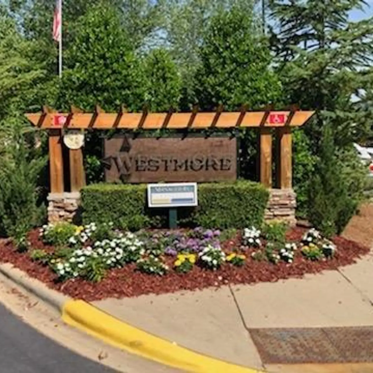 Sign for Westmore surrounded by greenery and flowers.