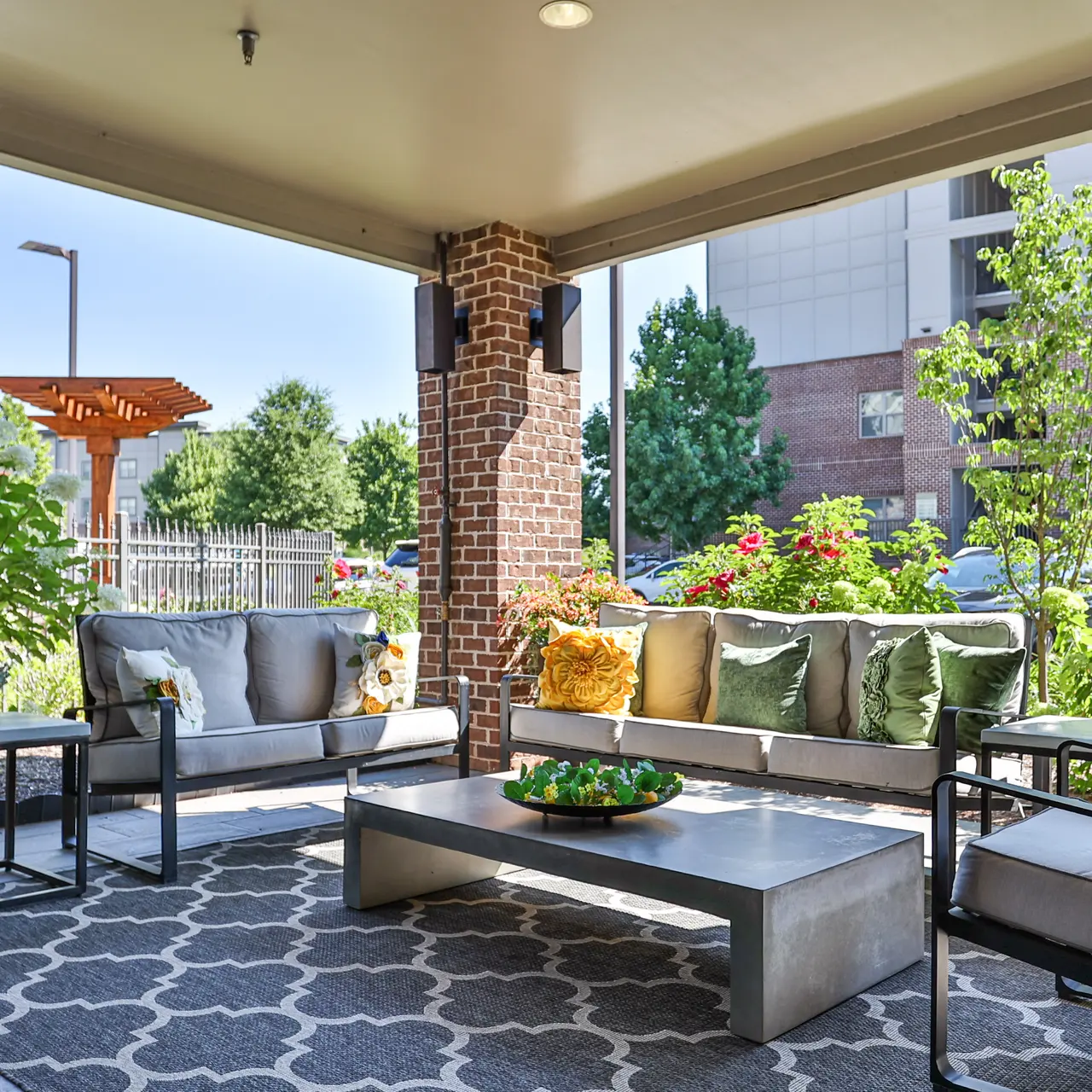 Cozy Outdoor Lounge Area A cozy outdoor lounge area featuring comfortable seating with cushions, a coffee table, and a decorative rug, surrounded by lush greenery and flowers.