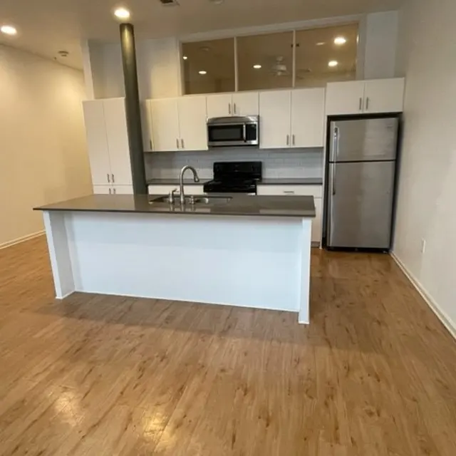 A modern kitchen with an island, stainless steel appliances, and white cabinets.