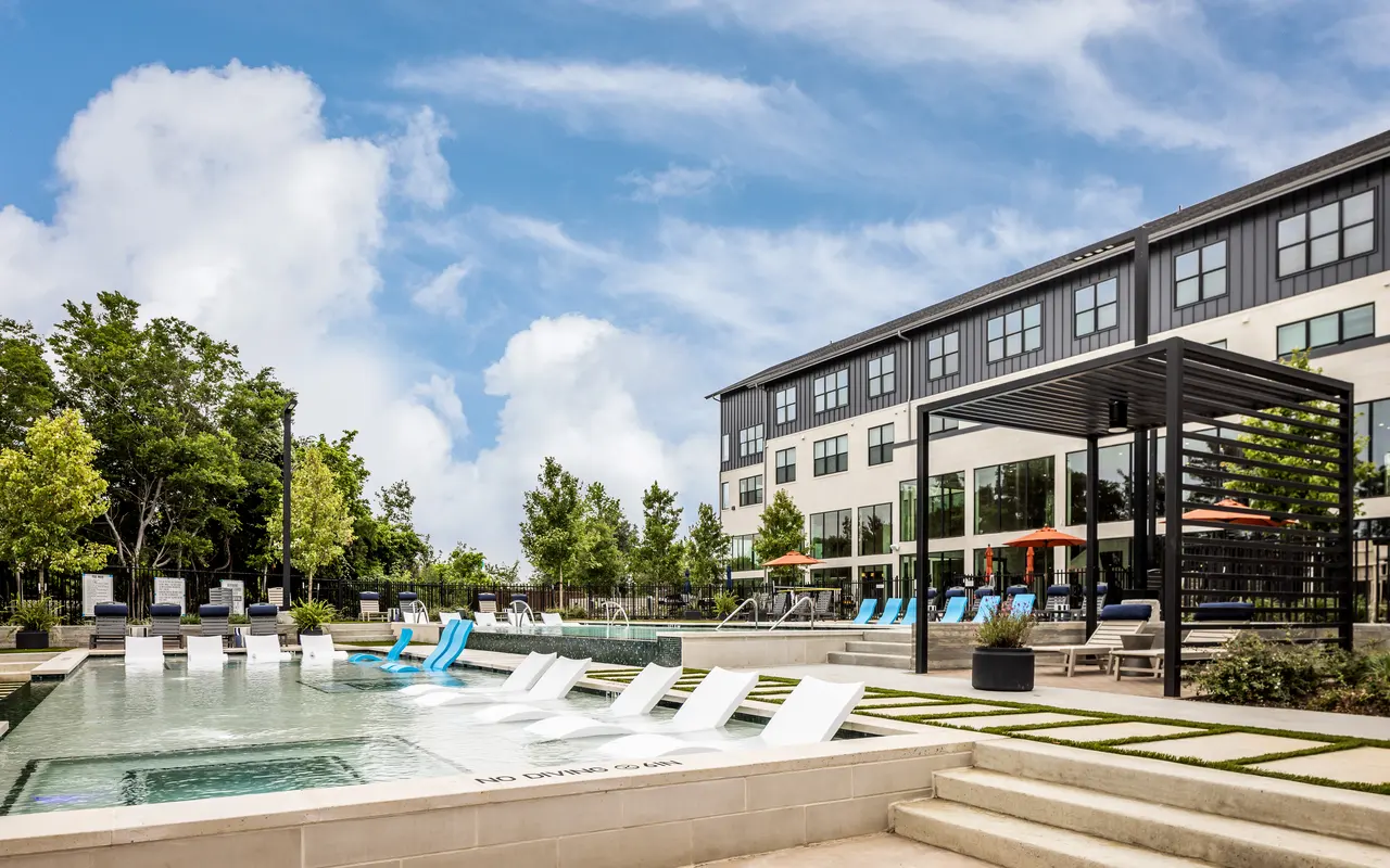 Swimming pool with lounge chairs in front of large trees at Standard on the River.