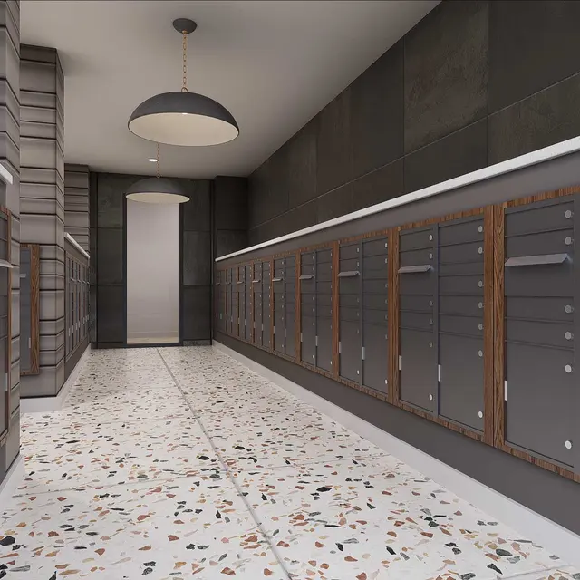 Interior view of a modern mailroom with gray mailboxes along the walls, stylish pendant lights, and a speckled floor.