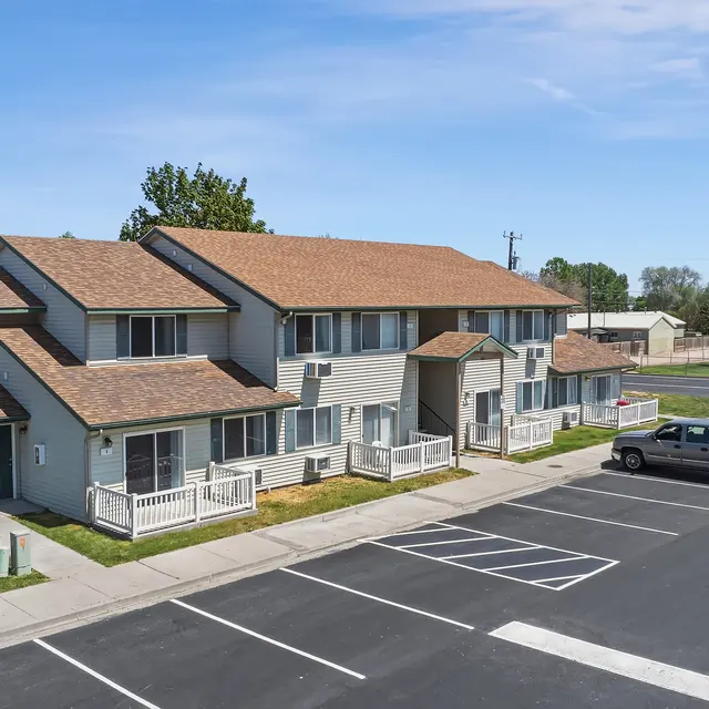 Aerial View of Apartment Complex Aerial view of a two-story apartment complex with multiple units, featuring a neatly landscaped lawn and a parking lot in the foreground.