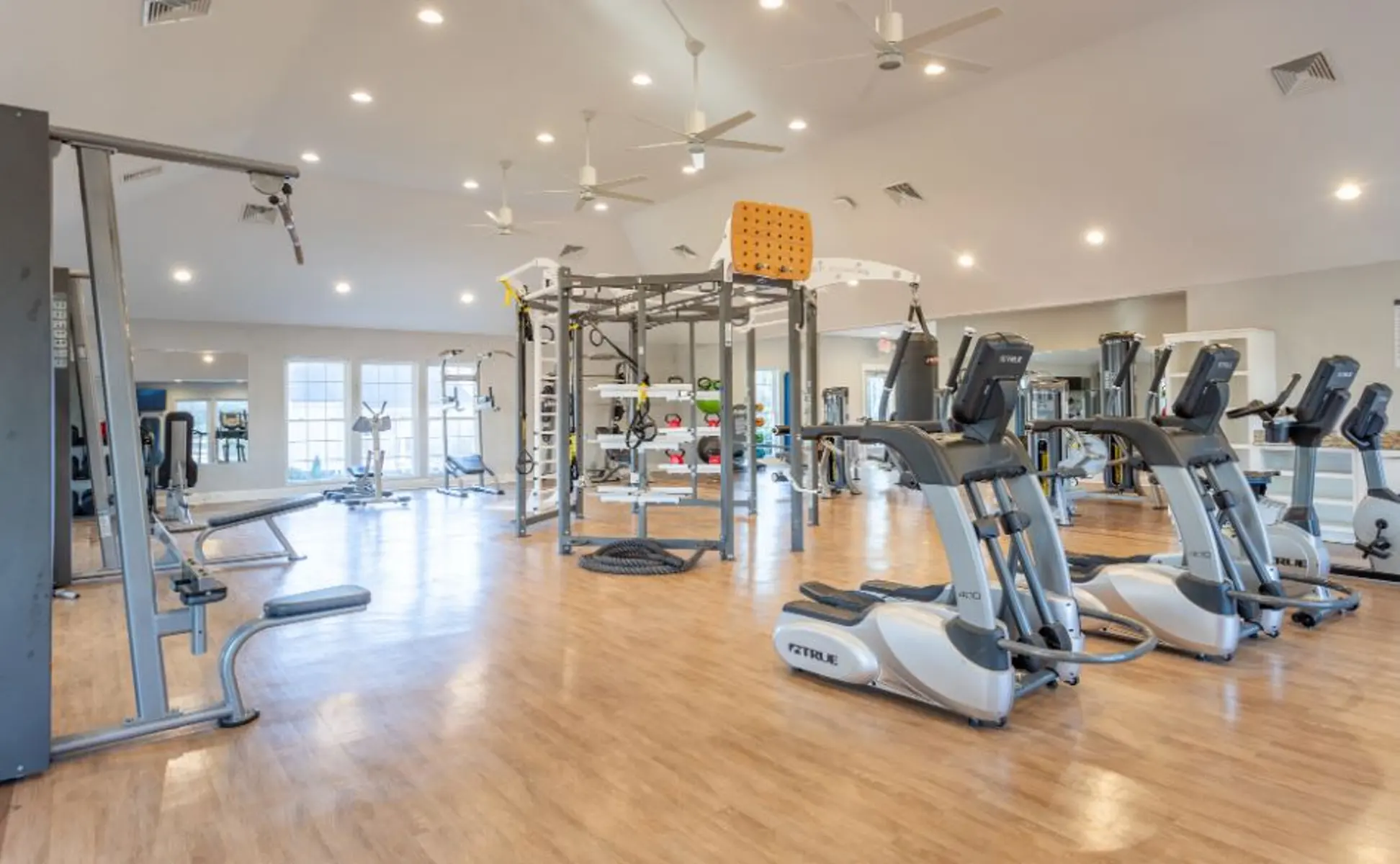 Interior of a modern gym featuring various exercise equipment including ellipticals, weights, and a multi-station fitness unit.