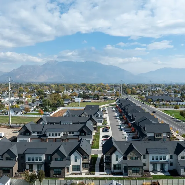 Aerial view of a suburban area featuring multiple modern houses and a clear sky with mountains in the background.