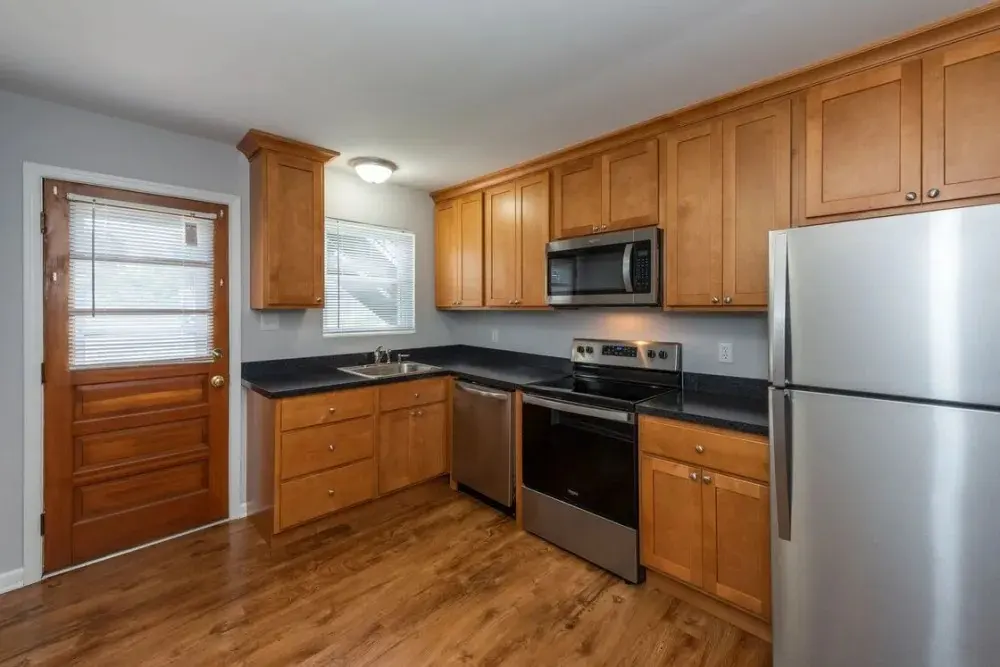 A modern kitchen featuring wooden cabinets, stainless steel appliances, and a door leading outside.