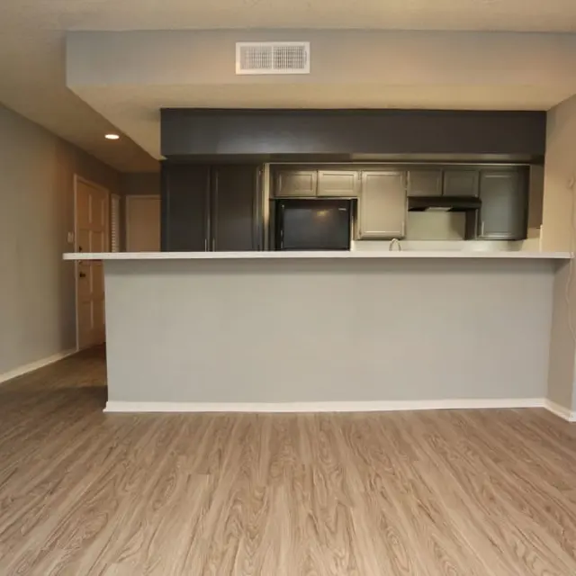 Modern apartment interior featuring an open kitchen and living area with laminate flooring.
