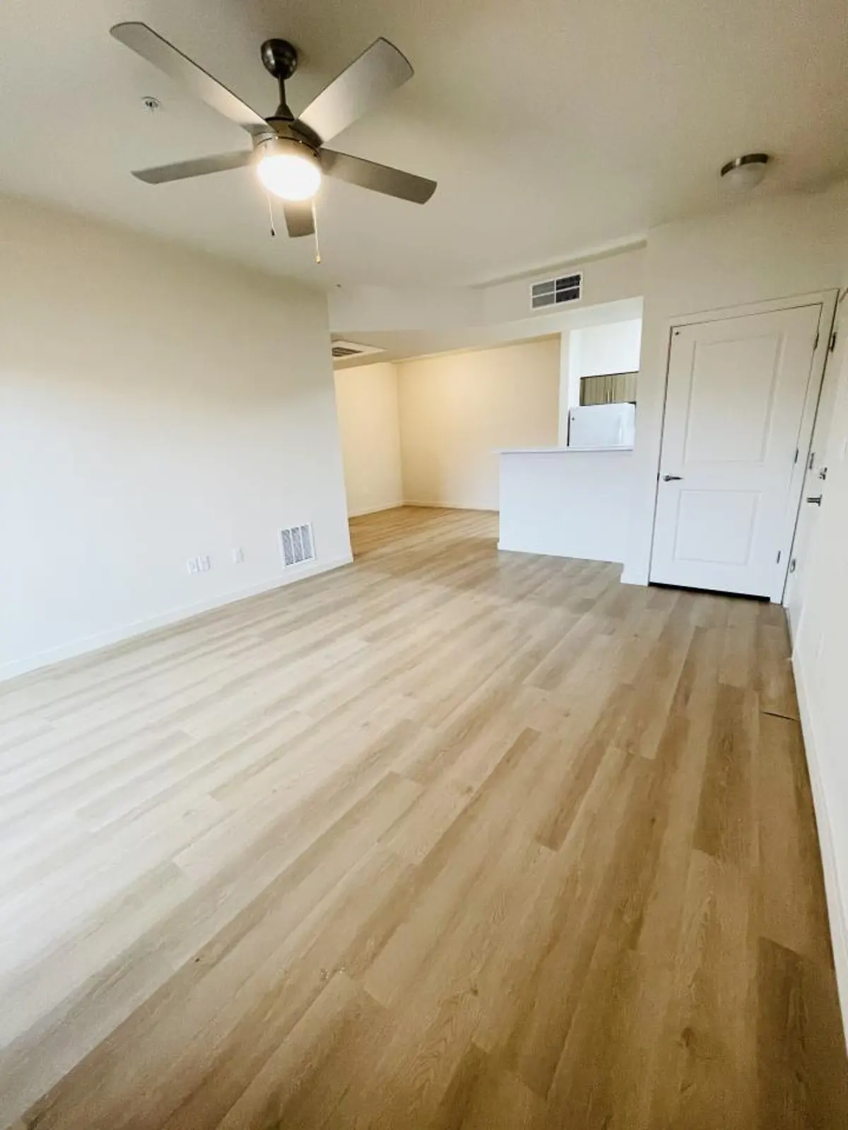 Living room with ceiling fan and kitchen counter.