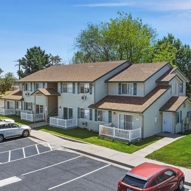Residential Apartment Complex Aerial view of a two-story apartment building with green lawn and parking lot.