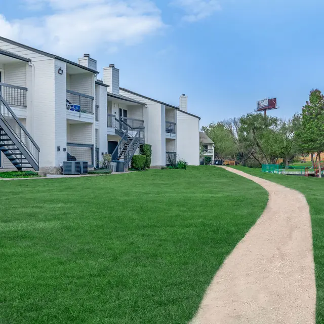 Walkway at Aviva at North Plaza surrounded by scenic grass and trees.