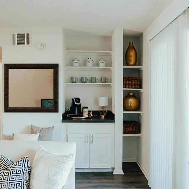 Living room with decorative shelving next to sliding glass door with white walls. 