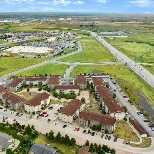 Eagle Ridge Aerial view of a large residential complex with multiple buildings, surrounded by roads and green fields under a blue sky.