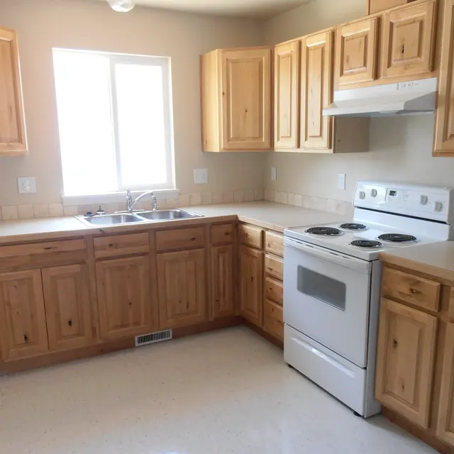 A kitchen with light wooden cabinets, a white stove, and a window providing natural light.