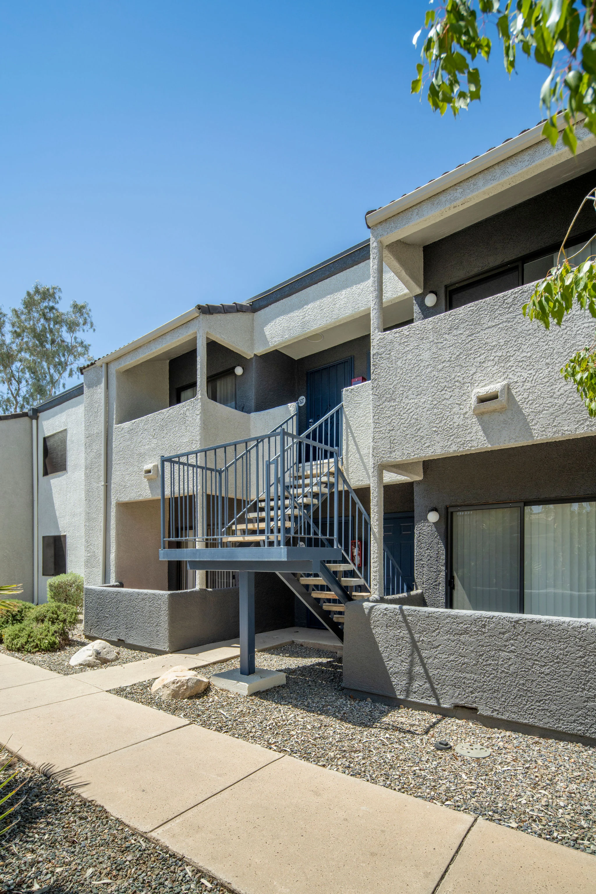 Exterior view of an apartment building with a staircase and landscaping