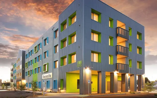 Contemporary Apartment Building Design A modern apartment building featuring a distinctive design with blue siding and green window frames. The structure has multiple levels and balconies.