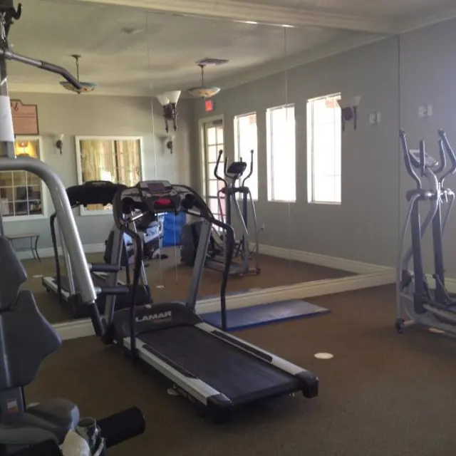 Compact Gym Interior Interior of a small gym with various exercise equipment including a treadmill, elliptical, and strength training machine.
