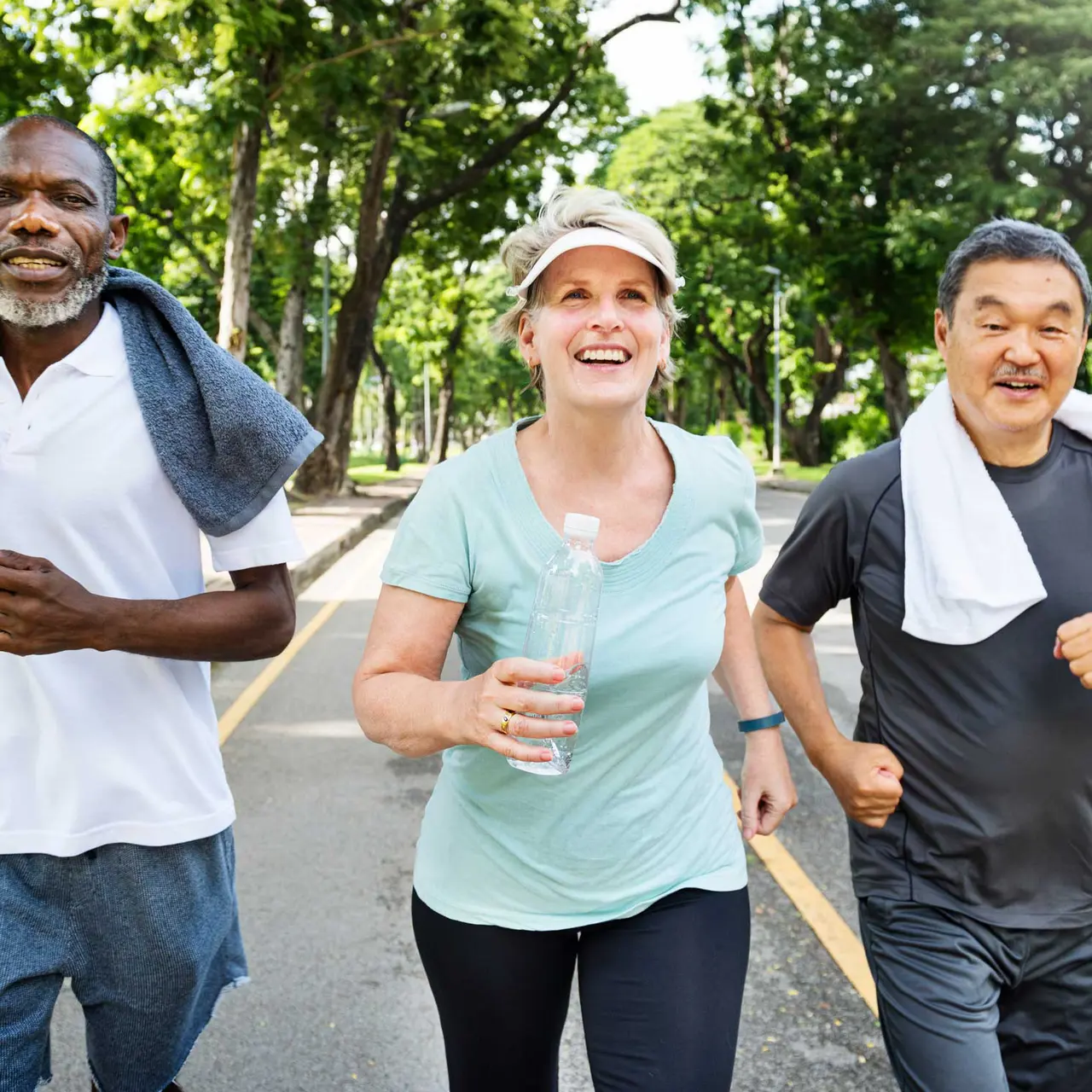 Jogging Together in the Park A diverse group of three people jogging together on a sunny day. Two men and one woman, all smiling and enjoying their exercise, with trees lining the path behind them.