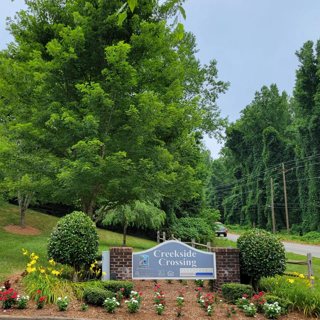 Sign for Creekside Crossing with landscaped flowers and greenery